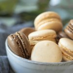 Assorted French macarons in a ceramic bowl, showcasing their delicate textures and pastel colors.